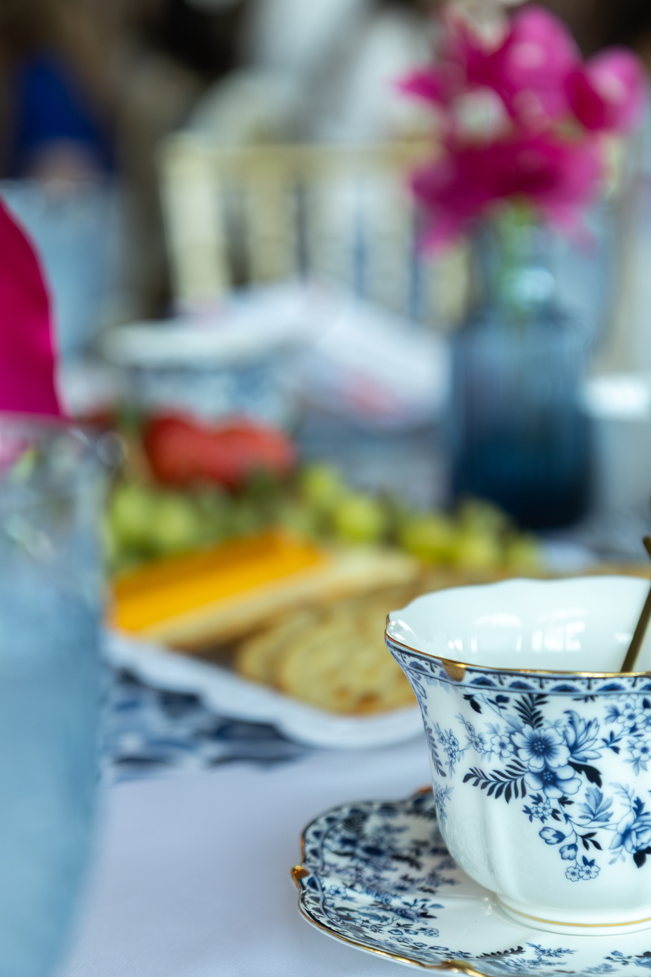 Soft-focus tea cup and pink flowers on a decorated table.