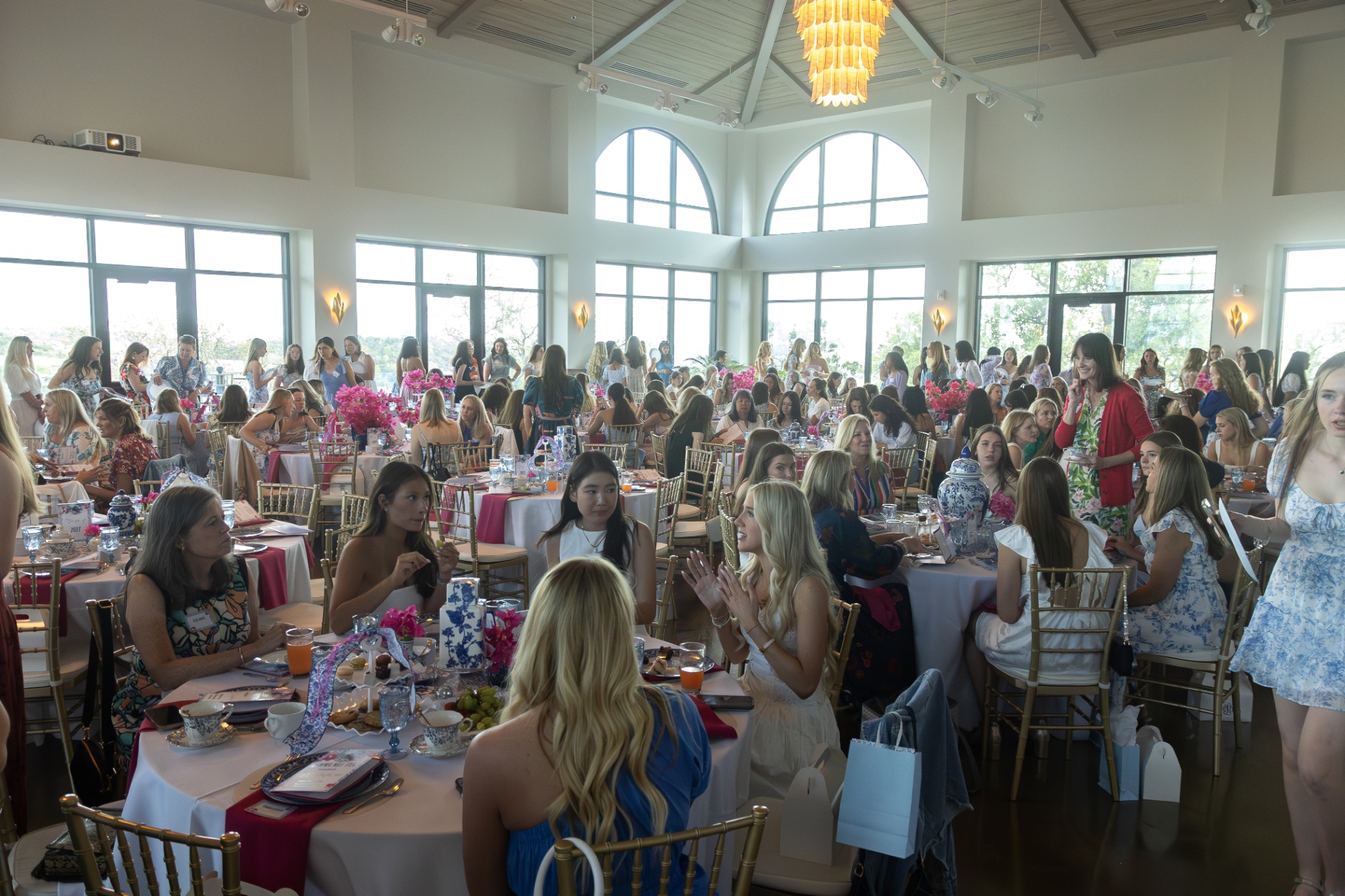 Ballroom filled with guests seated at decorated tables for a daytime event.