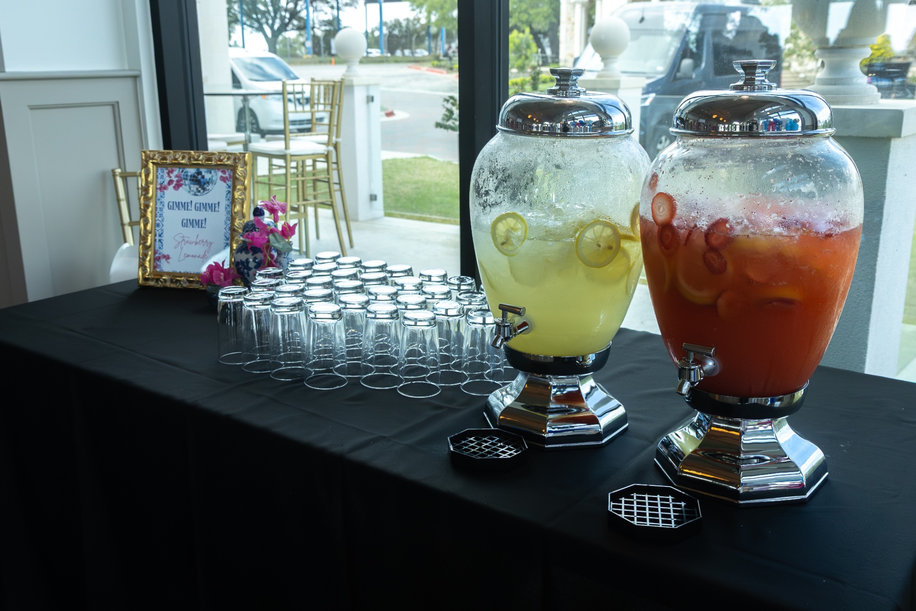 Beverage station with glass dispensers of pink and yellow lemonade.