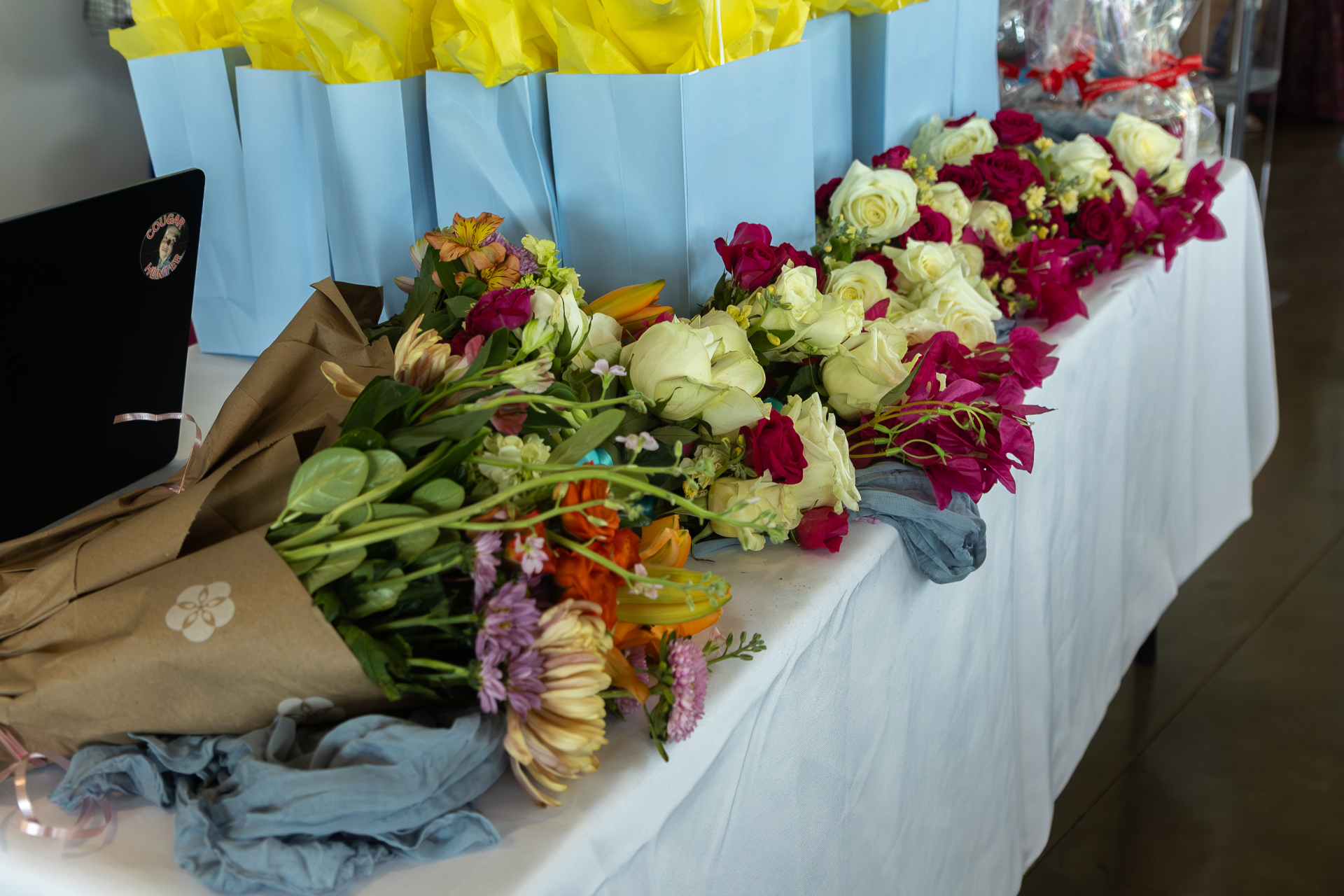 Row of floral bouquets on a white-clothed table.