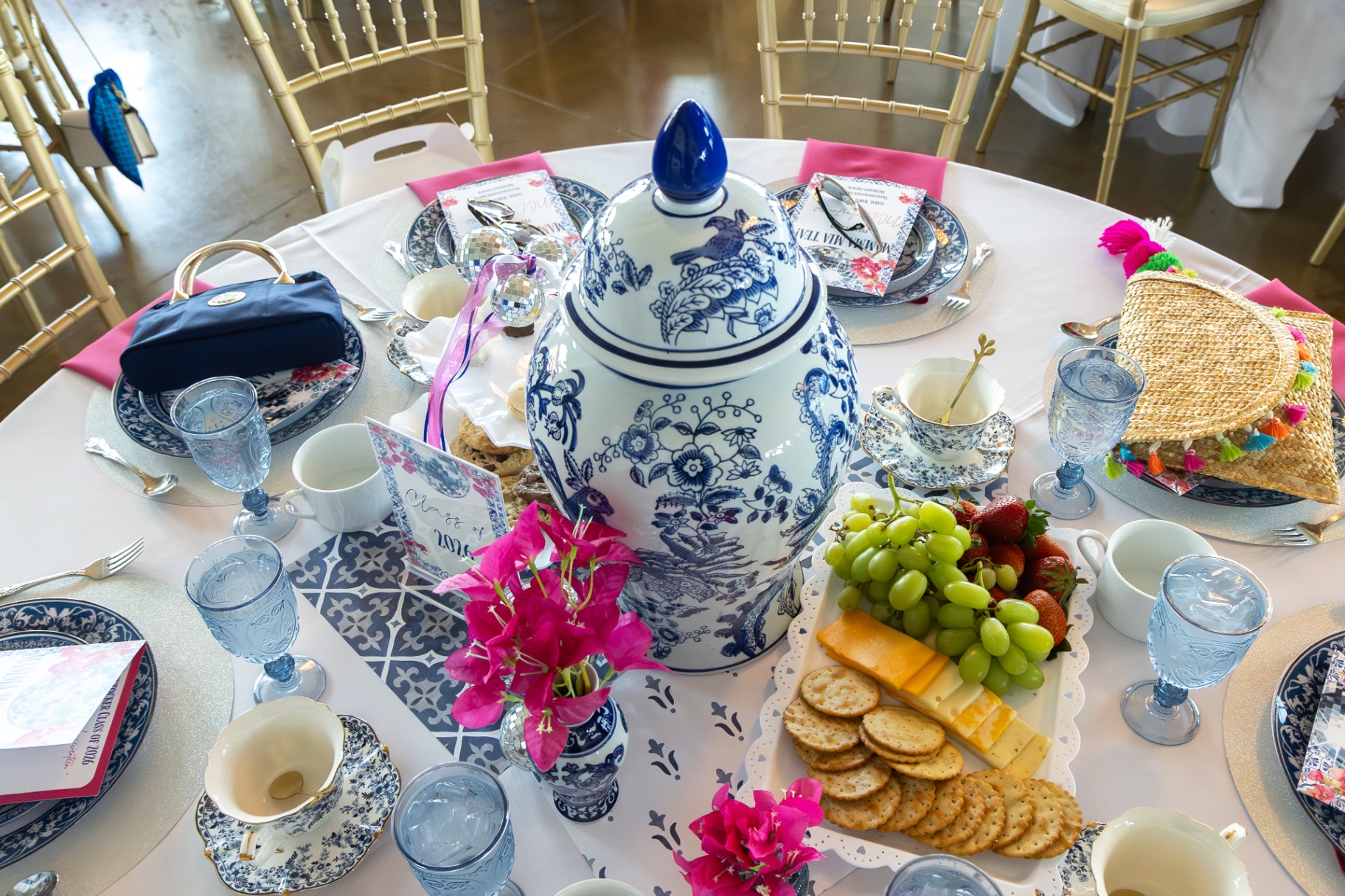 Wider view of a colorful tablescape with gold chairs in the ballroom.