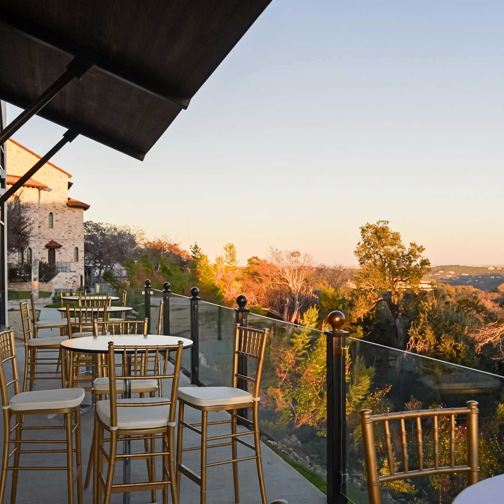Gold chiavari bar stools on the terrace overlooking the Hill Country at golden hour.