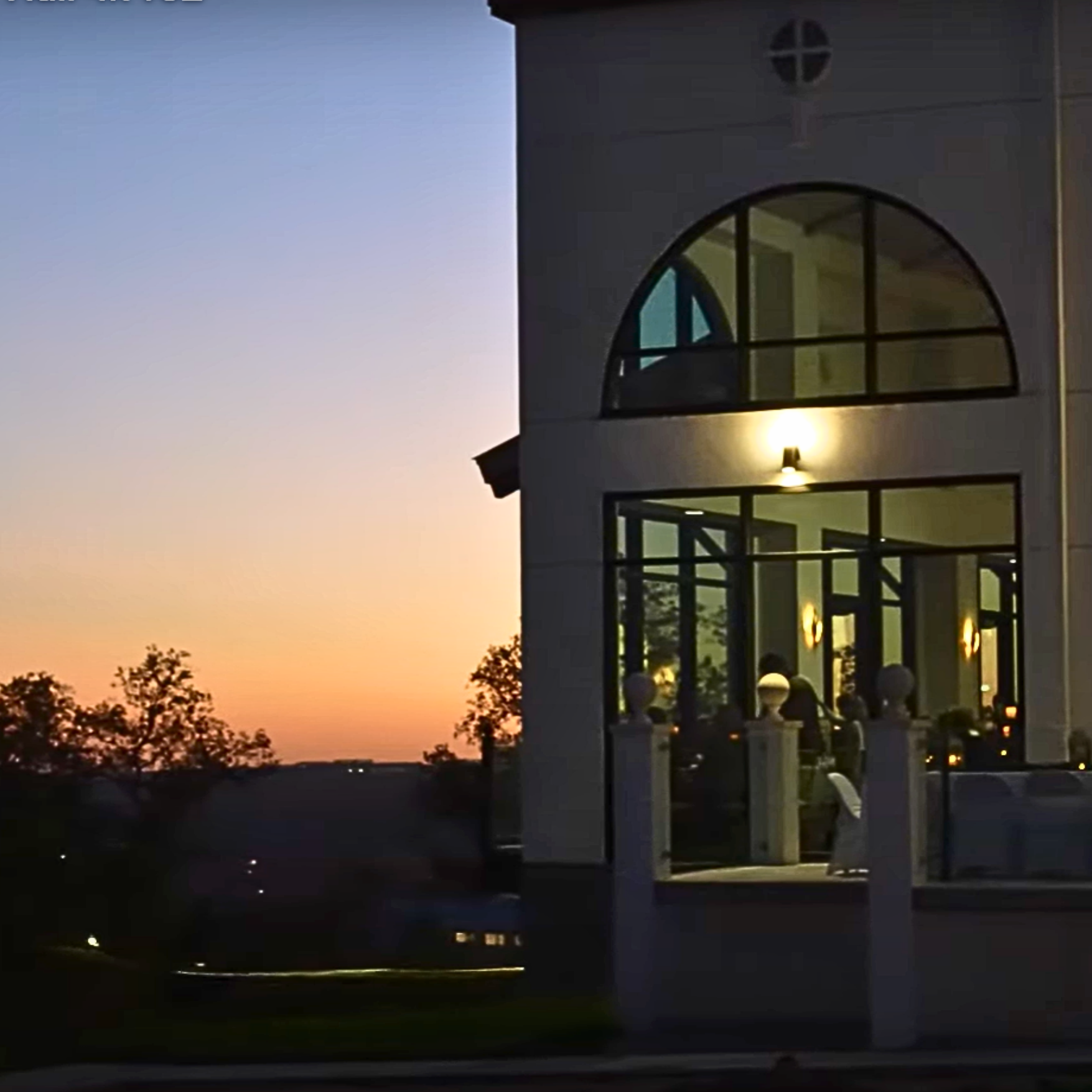 Ballroom windows glowing warmly at dusk.