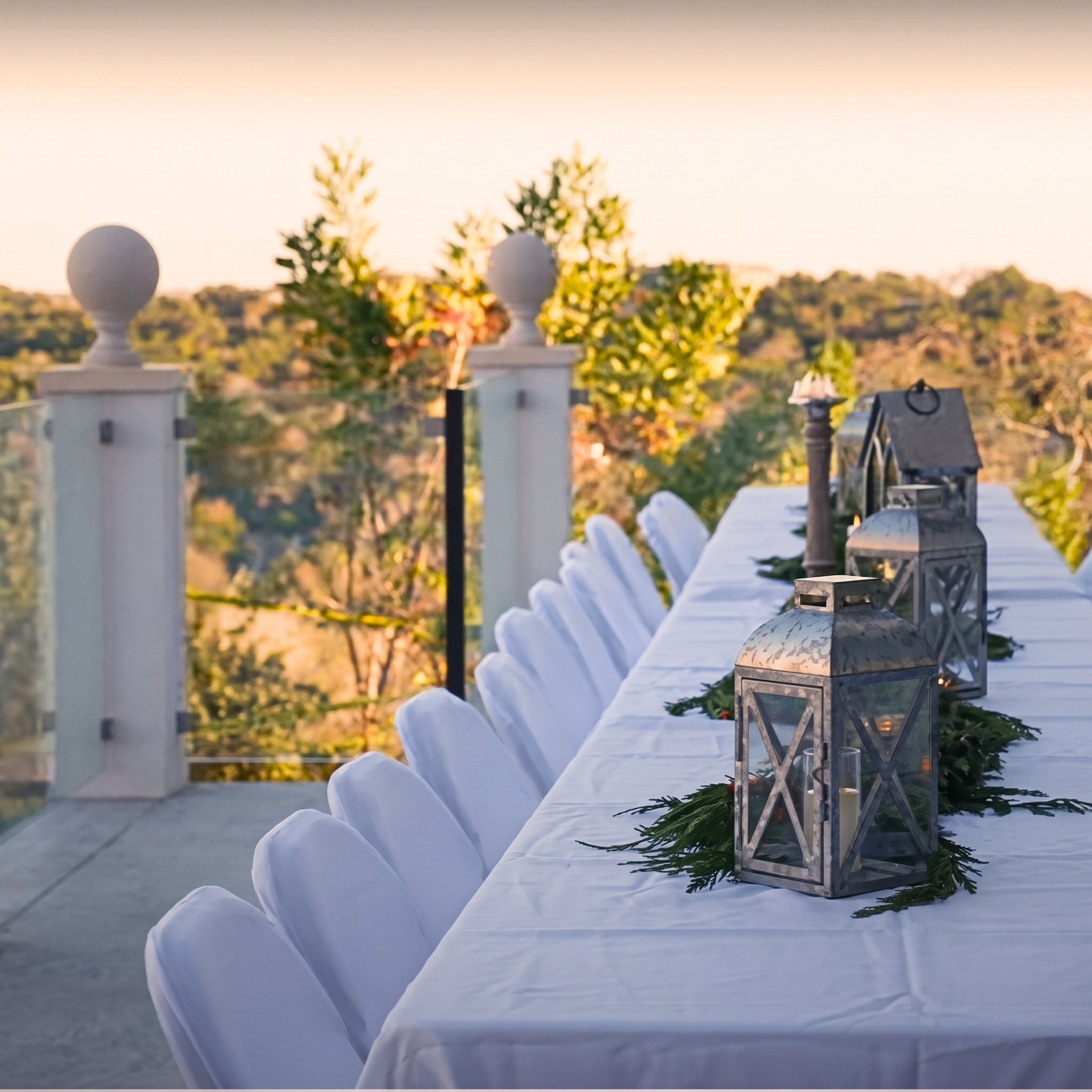 A long outdoor dining table dressed with linens and lanterns on the sunset terrace at The Pinnacle at Westlake.