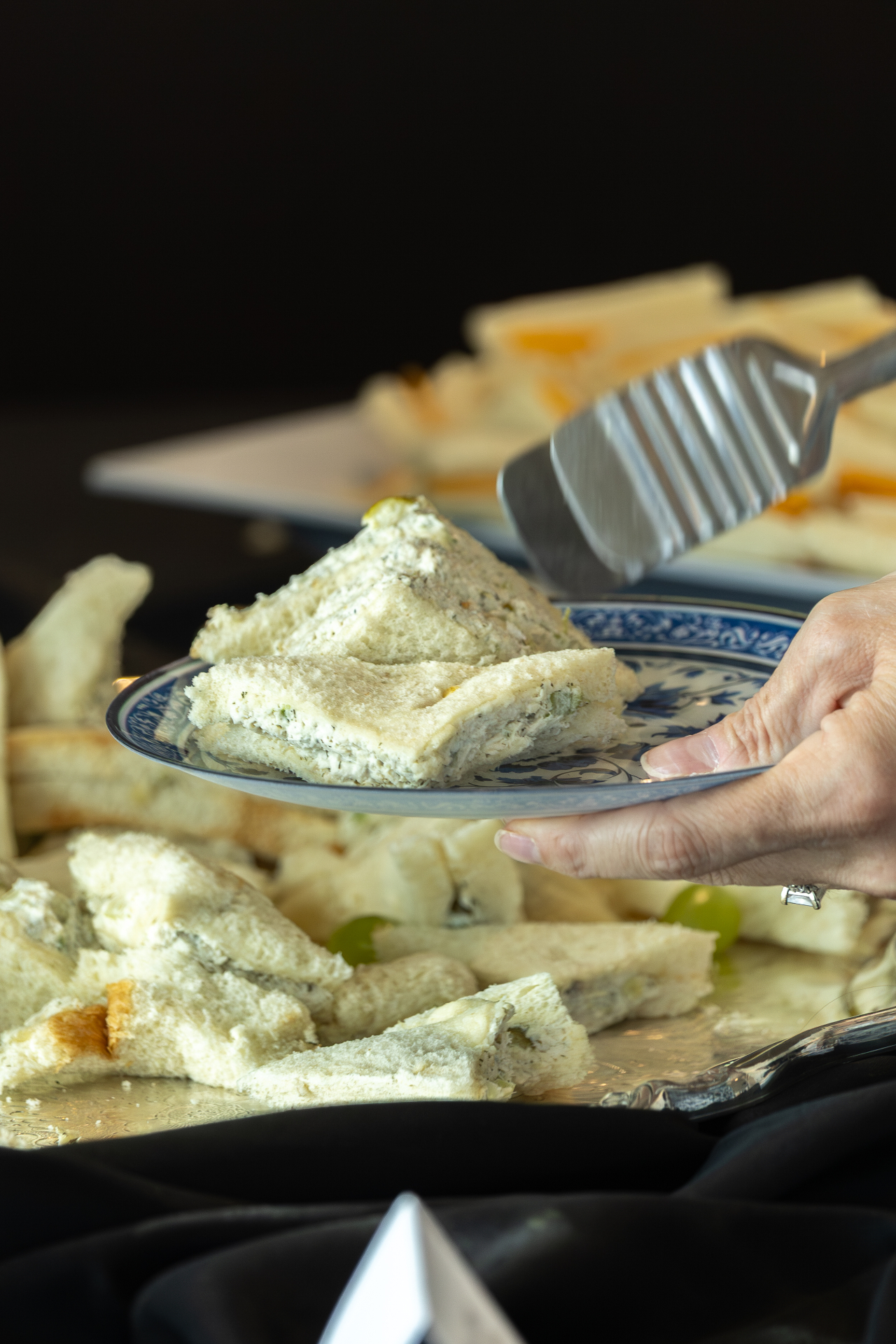 Guest using tongs to select a sandwich from a catering platter.
