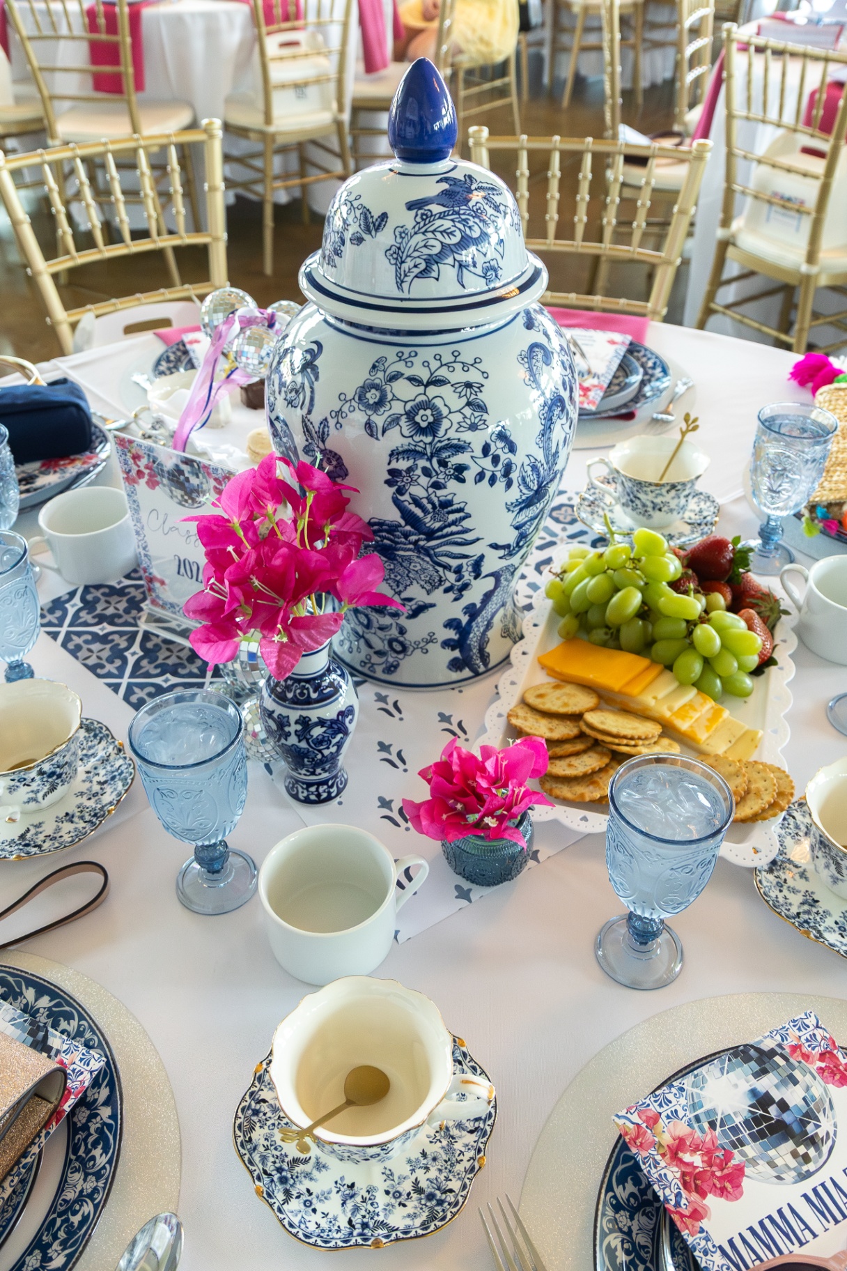 A vibrant blue and white tablescape with pink florals set for a private celebration.